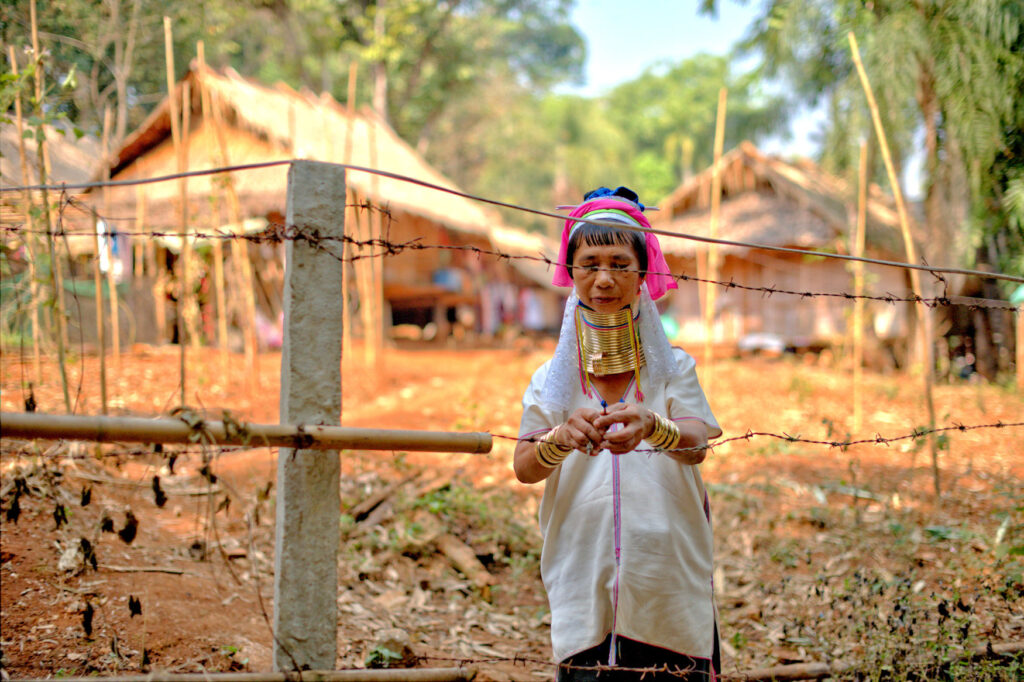 Long Neck Woman (Kayan Lahwi) repairing fences at her settlement home in Northern Thailand.