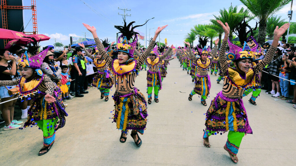 Dancers represent their local community as they compete for a whole day, while thousands of onlookers line the street in support. Cebu City, Philippines.